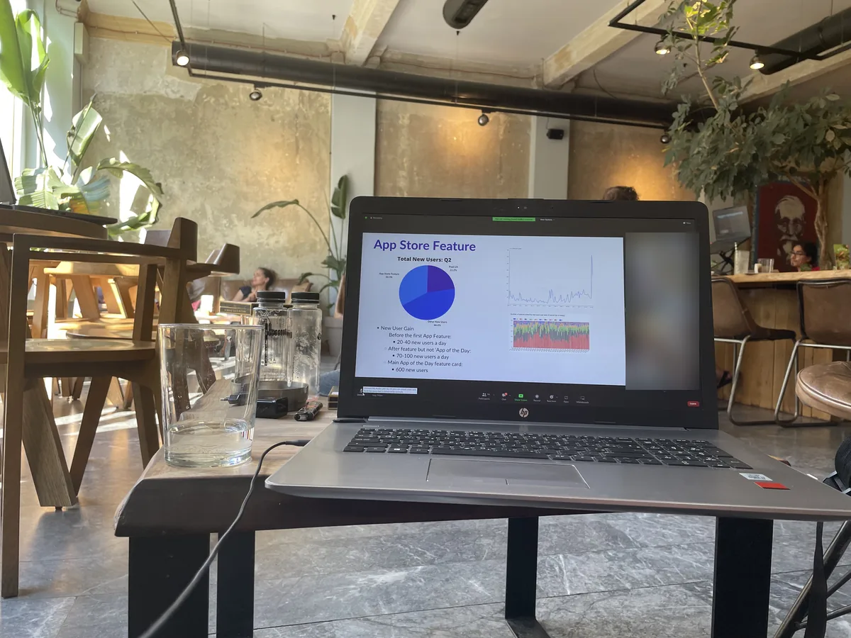 A laptop on a table showing a video call with a shared slide; faces of other participants are blurred